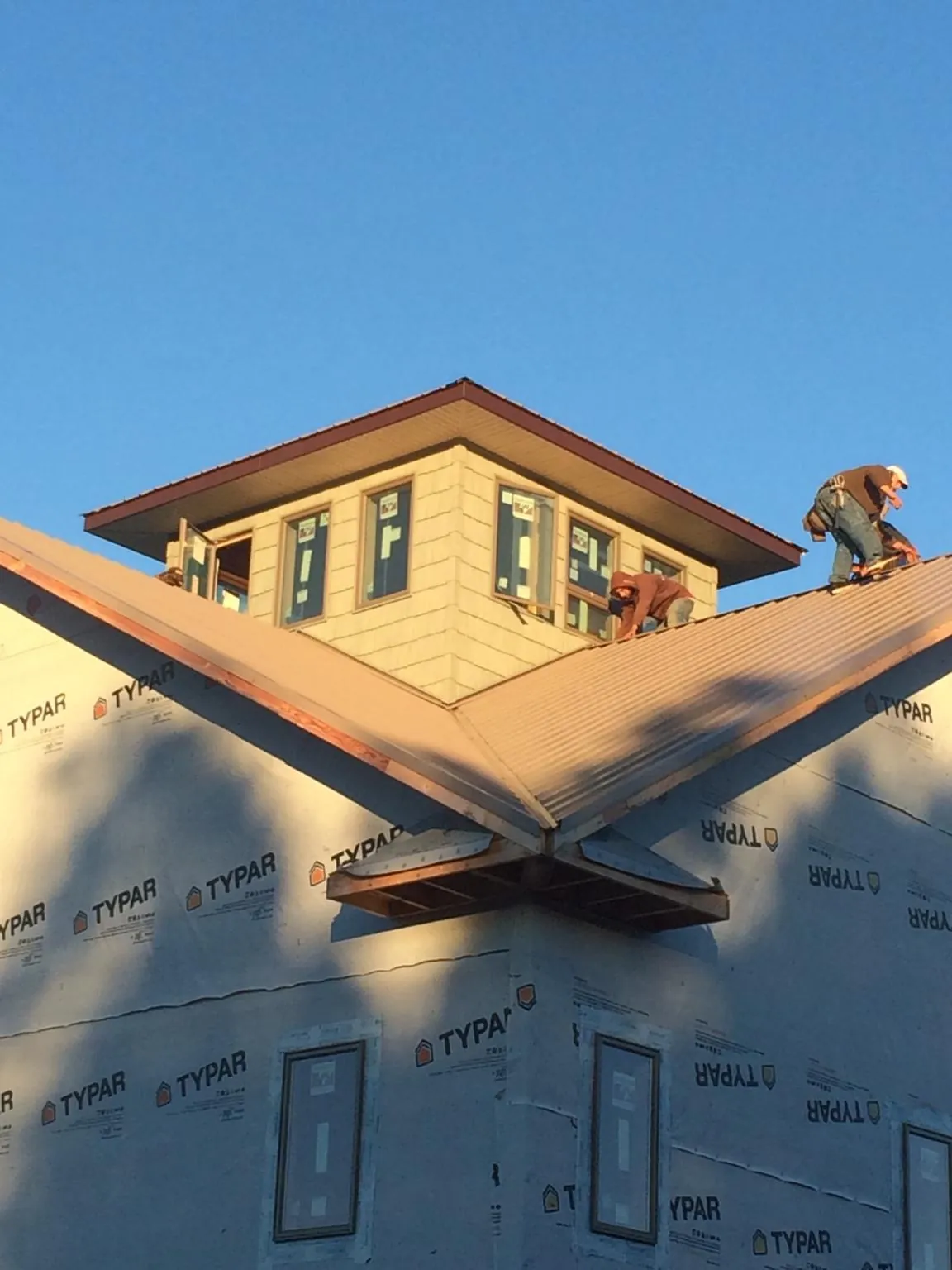 Roofers working around a rooftop cupola on a new metal roof at sunset — Roof Waterproofing in Minersville by Roofing Brothers